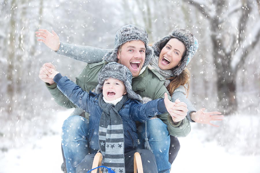 Personal Insurance - Family of Three Play in the Snow, Bundled up for the Cold Weather, Smiling Broadly